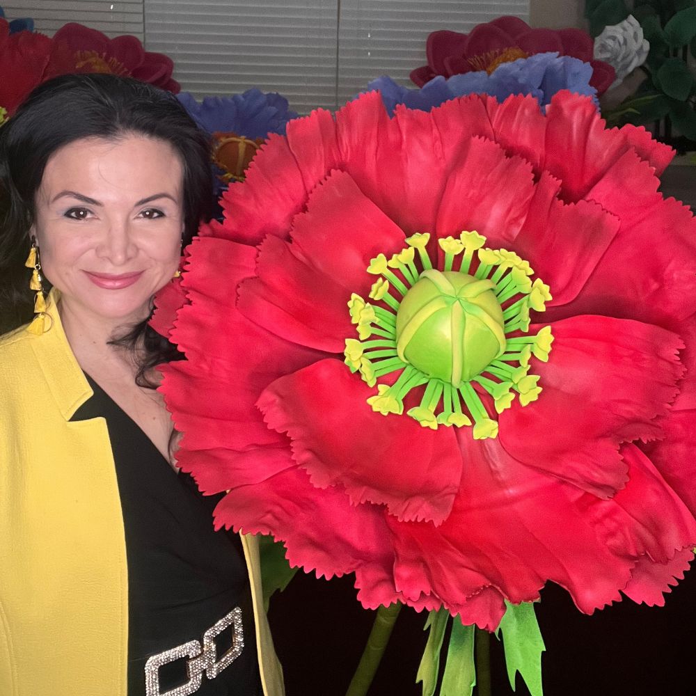 Adriana Wells holding a giant handcrafted red poppy flower