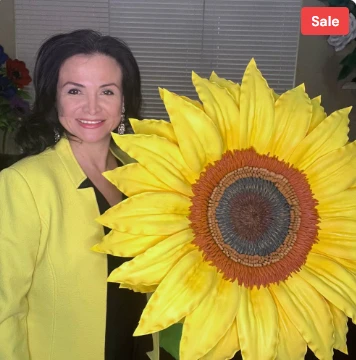 Adriana Wells holding a giant handmade sunflower in her yellow jacket